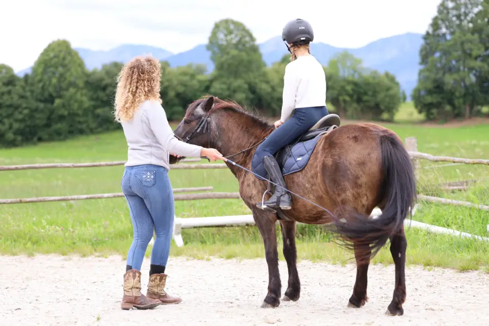 Kind reitet an der Longe auf dem Reitplatz vom Hof Gottenau