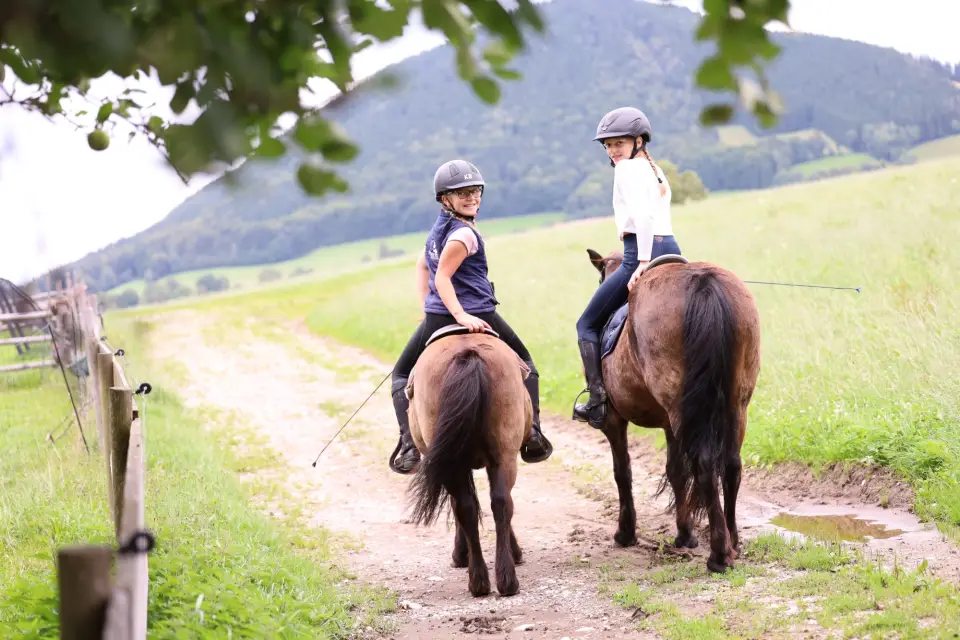 Zwei Kinder auf einem geführten Ausritt über den Feldweg